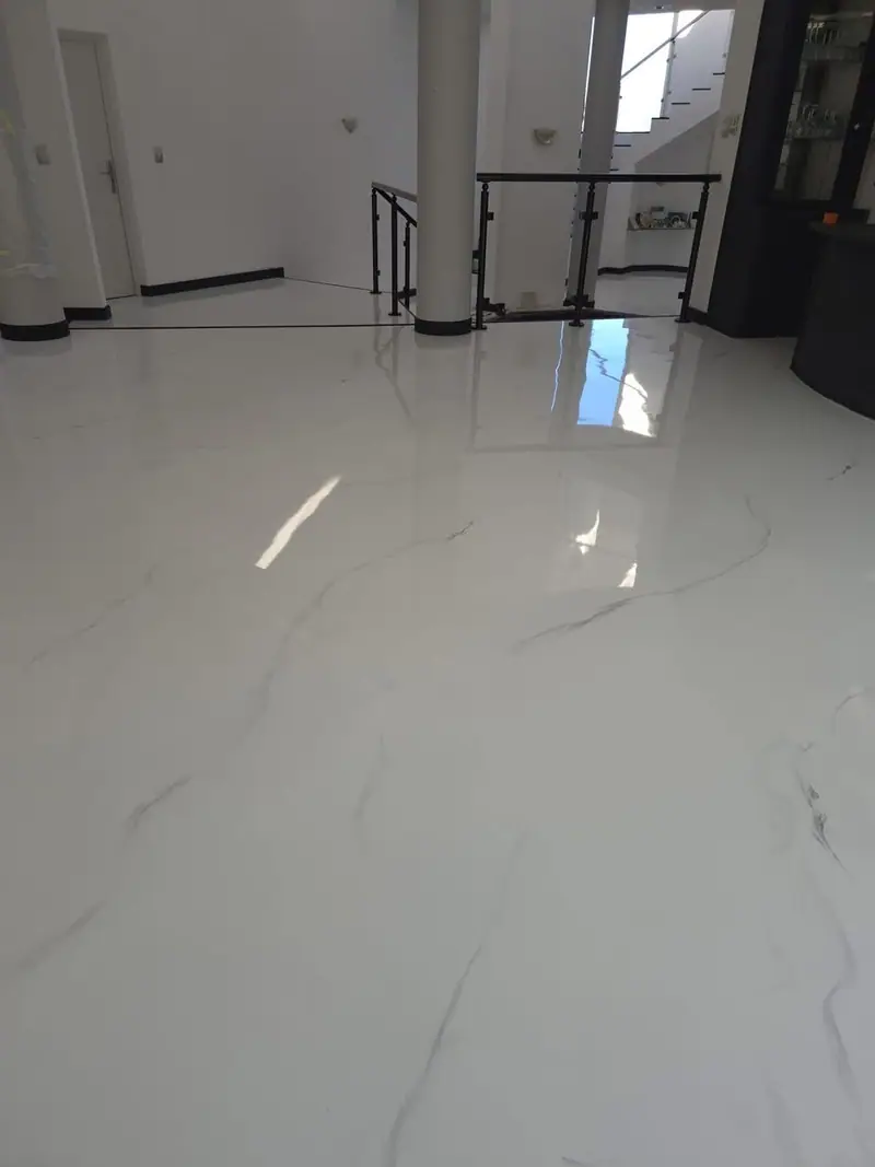 Glossy white epoxy floor with grey marble-effect veining, black skirting and a black balustrade