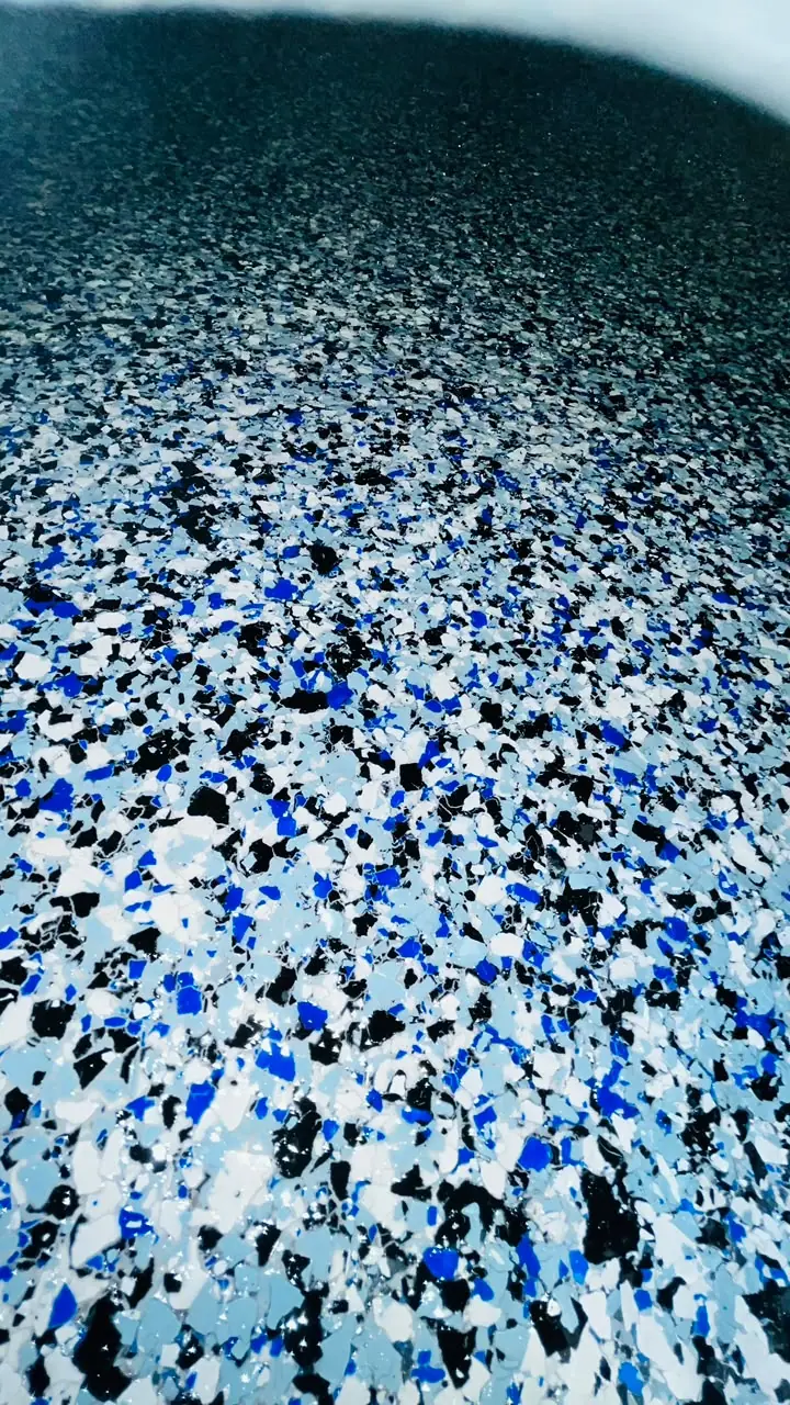 Close-up of a flake-finish epoxy floor in blue, black, white and grey flecks