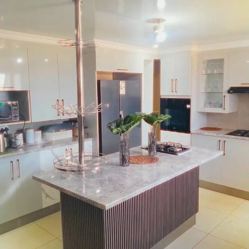 Island with a fluted timber panel in front of white gloss cabinets