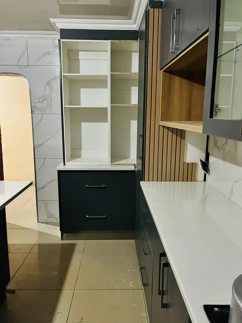 Open white shelving beside charcoal drawers and a fluted timber panel