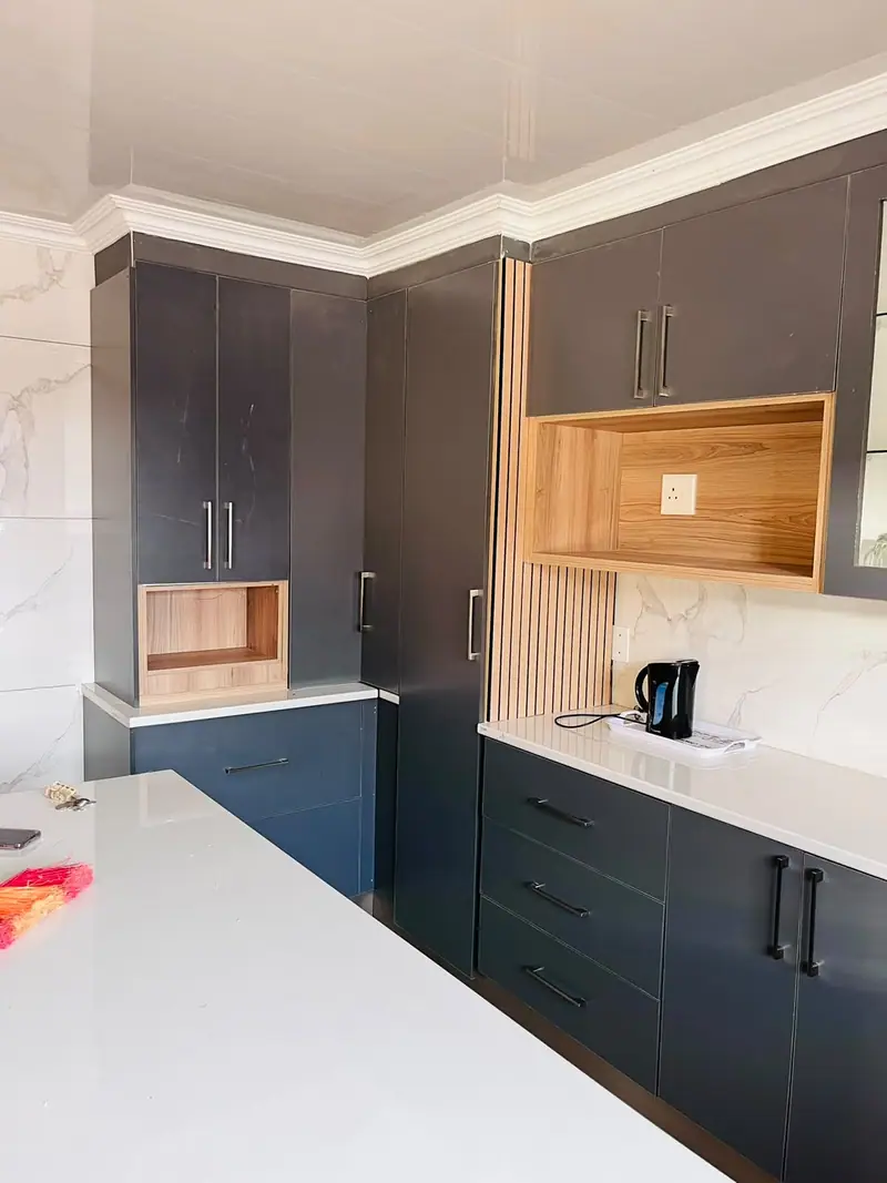 Tall charcoal cabinets with a timber niche beside a fluted timber panel