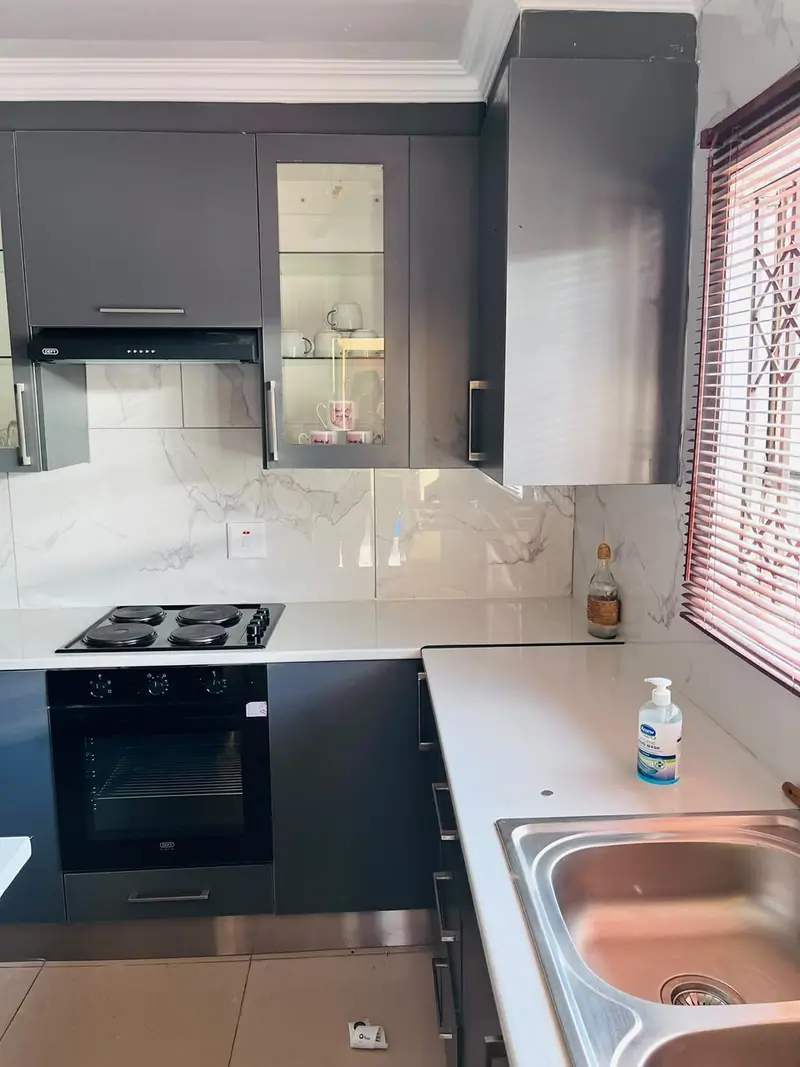 Charcoal kitchen with a glass-front cabinet beside an extractor and hob