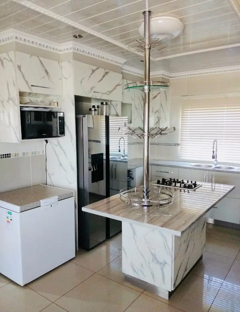 Kitchen with a marble-effect island, ceiling pole rack and white cabinets