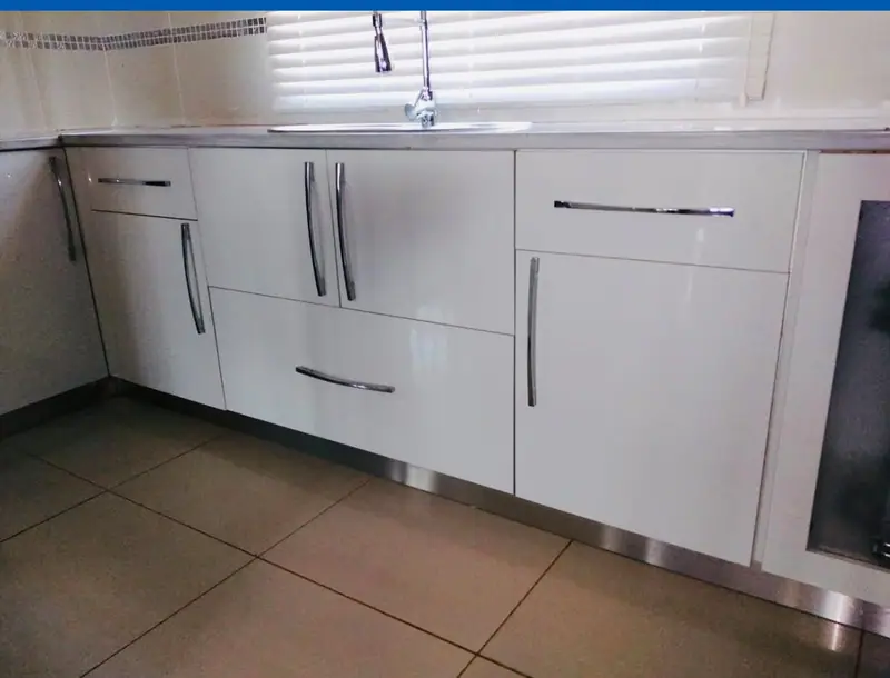 White gloss base cabinets with long bar handles and a sink