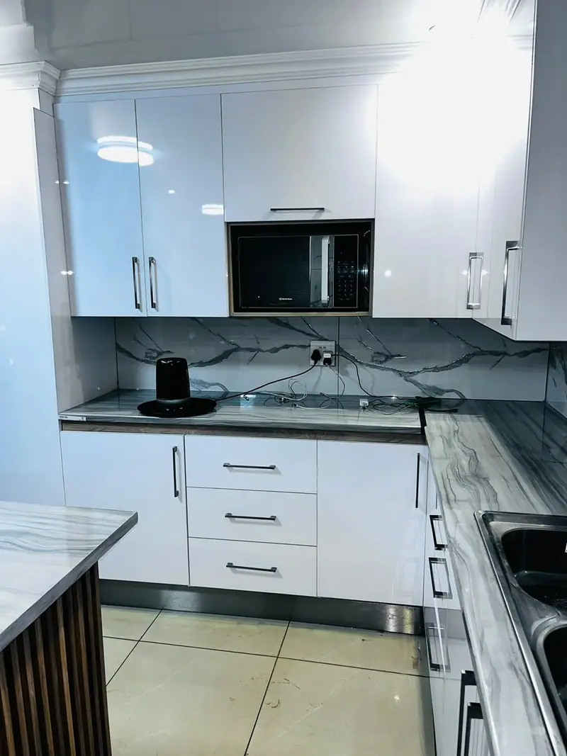 White gloss kitchen with a marble-effect splashback and built-in microwave