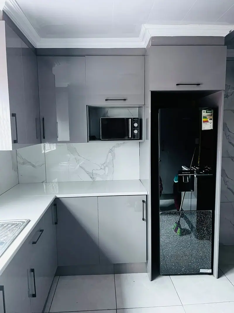 Grey kitchen with a built-in microwave beside a tall black fridge