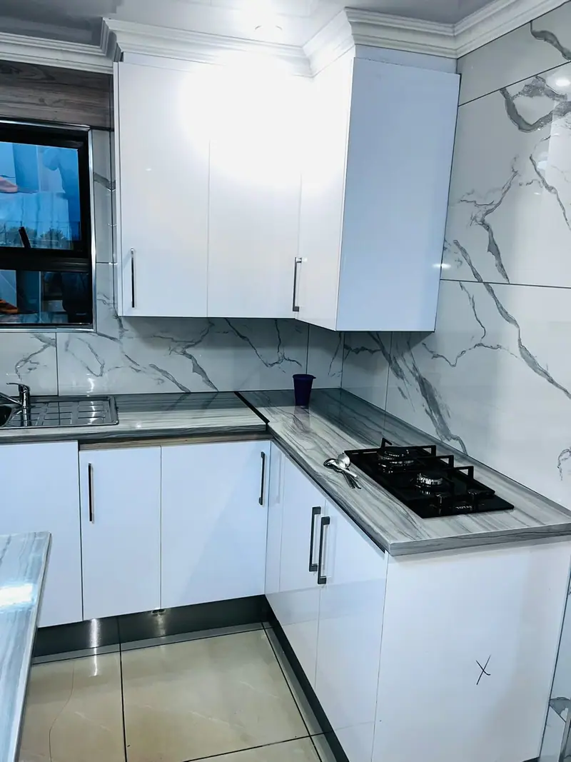 White corner kitchen with a marble-effect splashback and gas hob