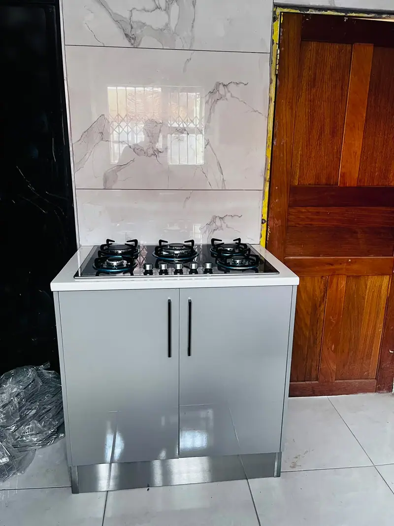 White base unit with a gas hob and black handles