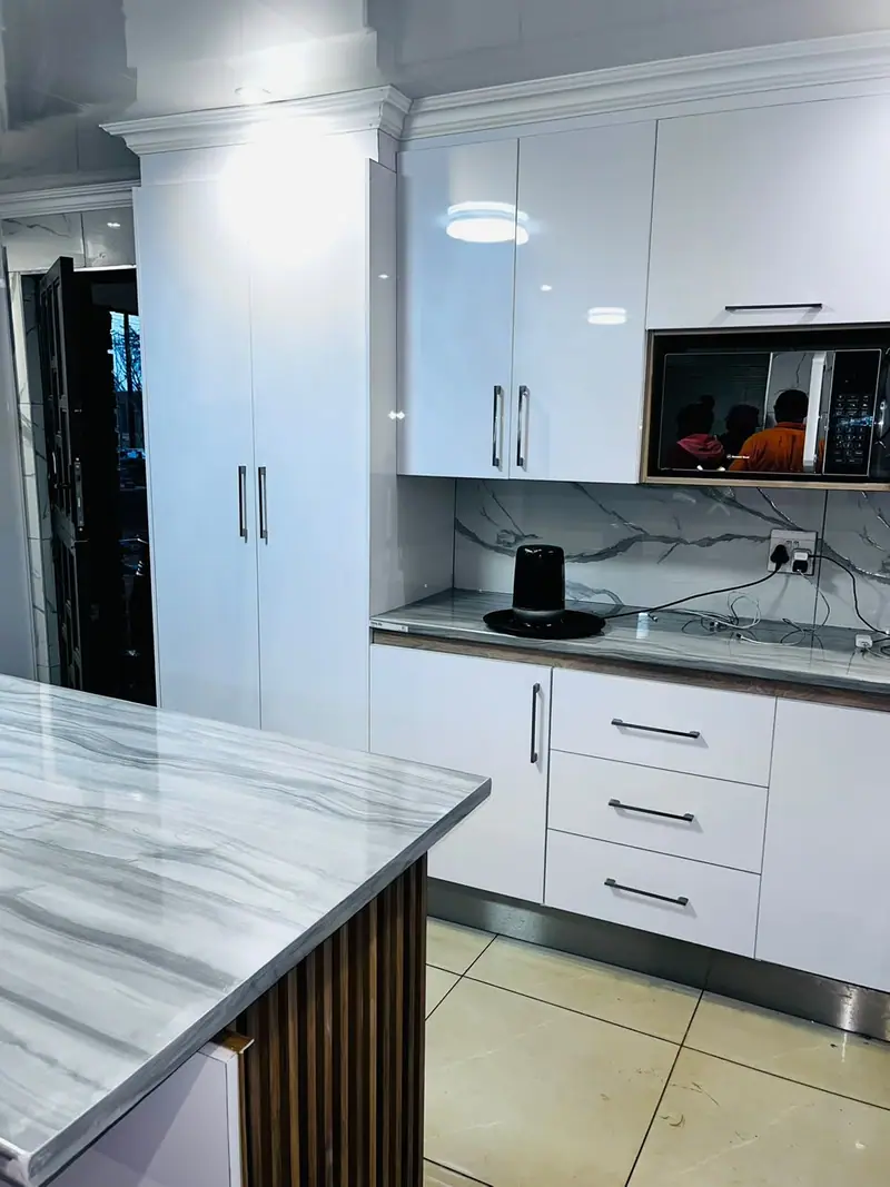 Tall white gloss cabinets beside a marble-effect island top