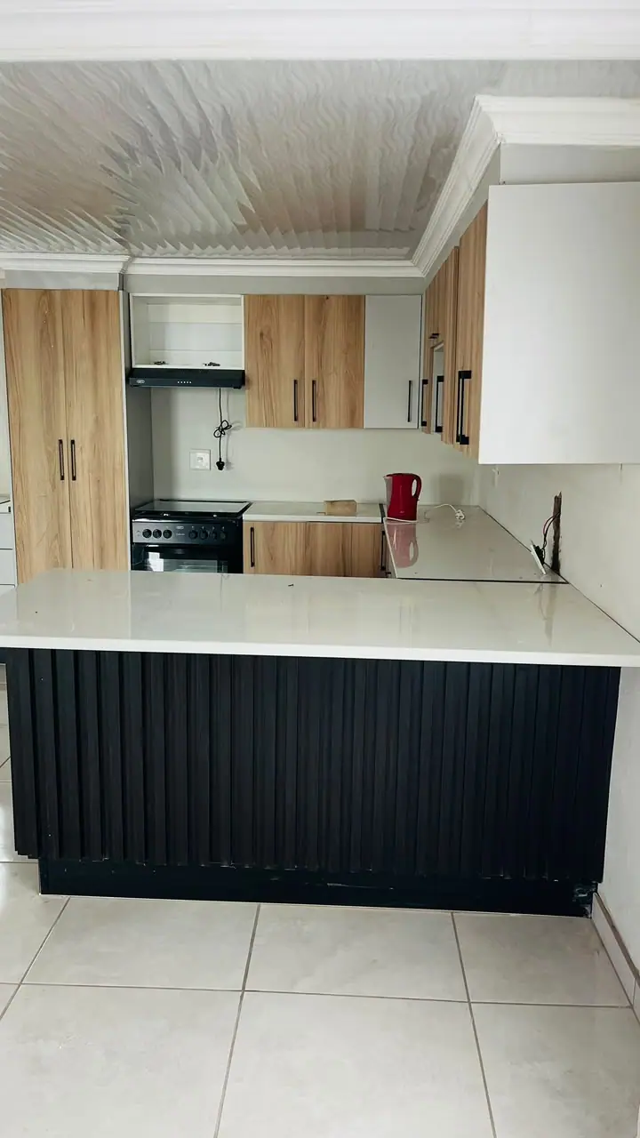 Kitchen peninsula with a black fluted front and timber-effect tall units