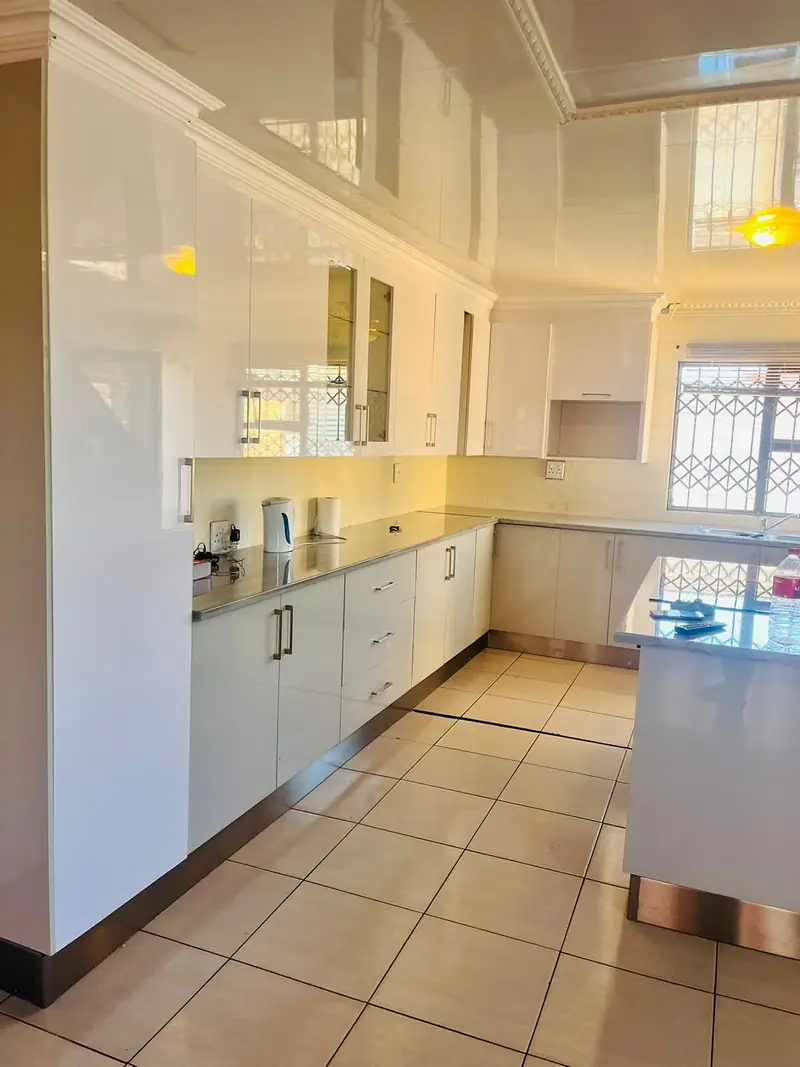 Long white gloss kitchen run along a tiled floor