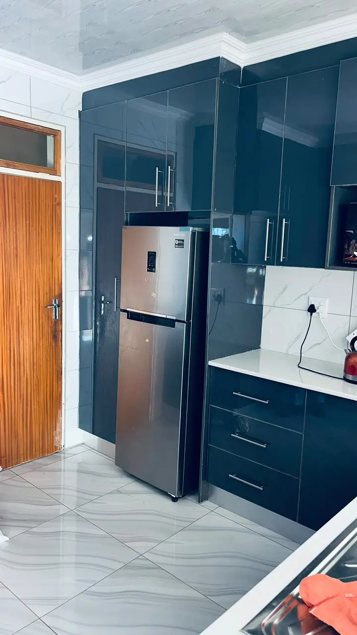 Tall navy gloss cabinets beside a stainless steel fridge