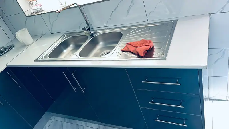 Navy gloss drawers beneath a stainless double sink