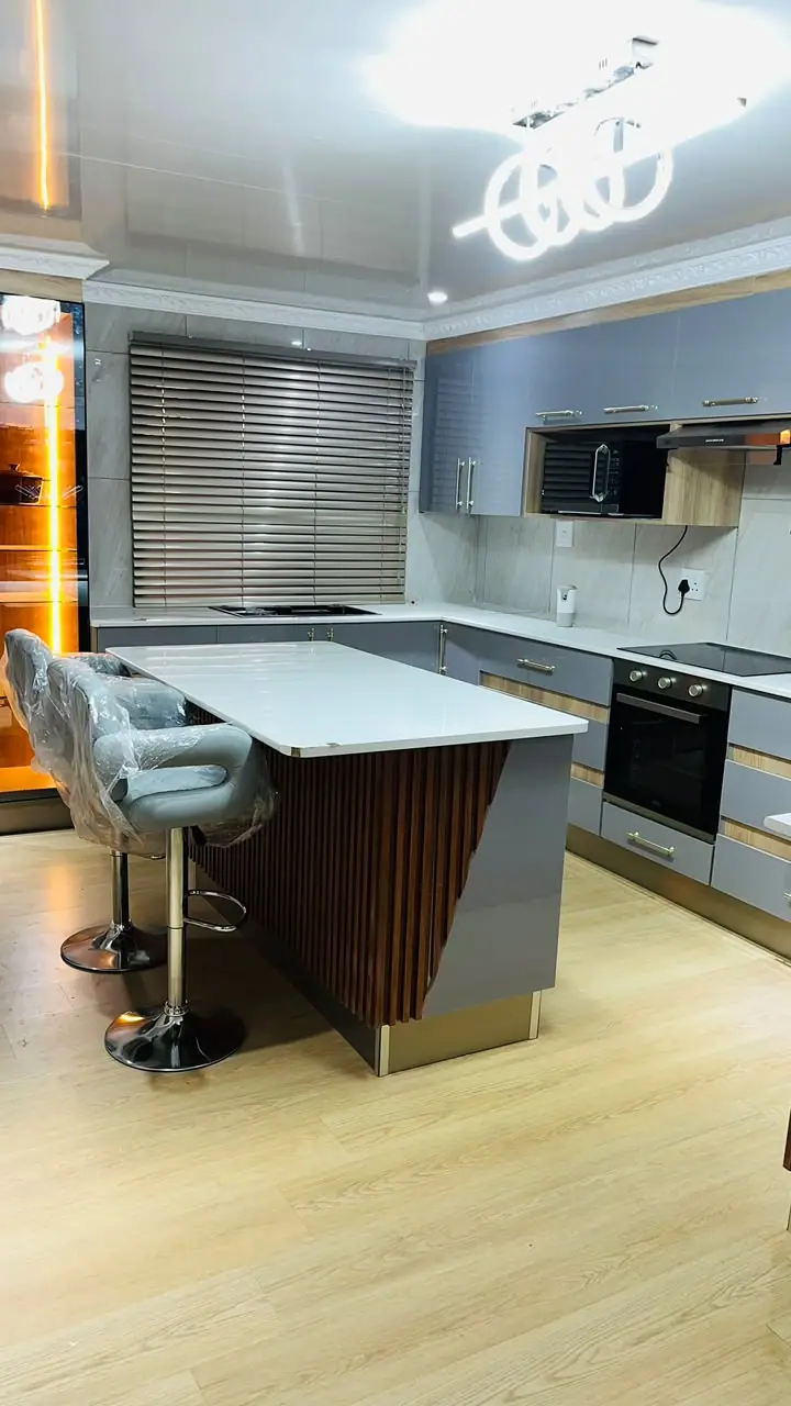 Kitchen island with a slatted timber side and bar stools, grey cabinets behind