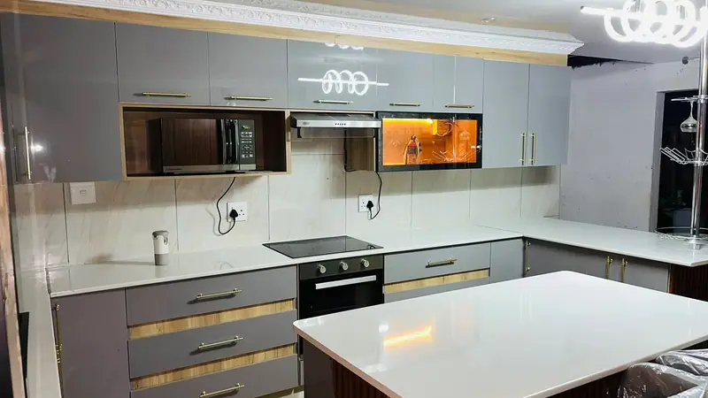 L-shaped kitchen with grey high-gloss cabinets, a timber-framed microwave niche and a white island