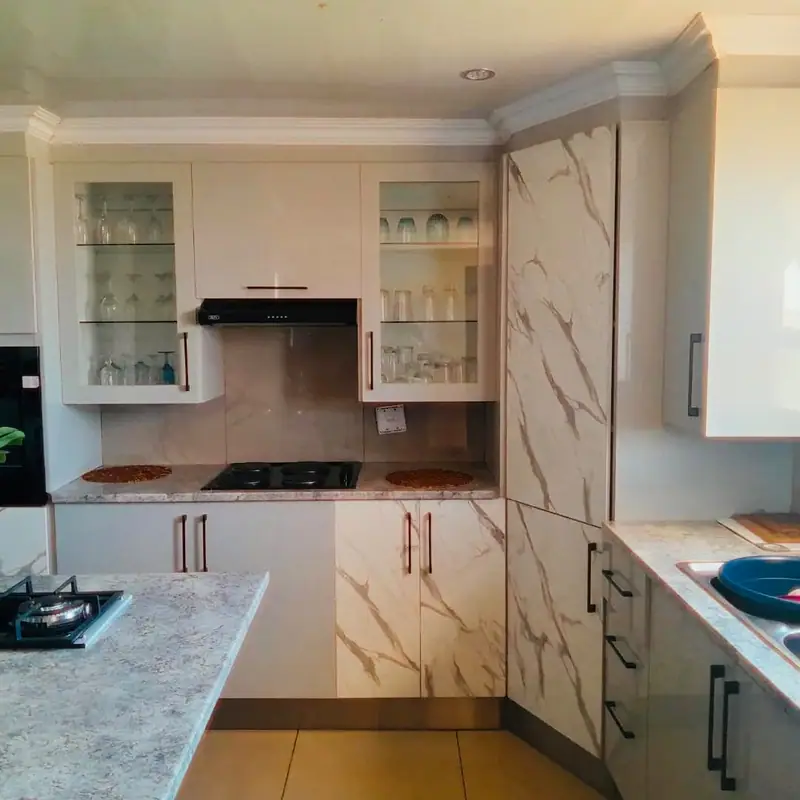 White and marble-effect kitchen with glass-front wall cabinets and black handles