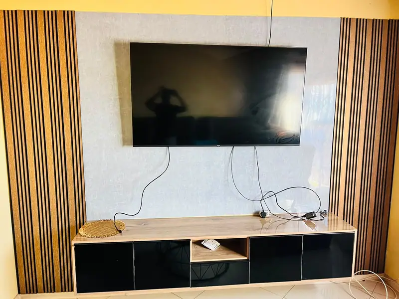 Black-fronted TV unit with a timber top between fluted timber panels