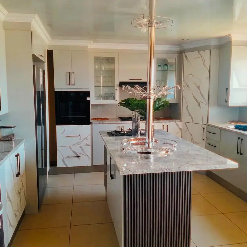 White gloss kitchen with a marble-effect island with a fluted timber side