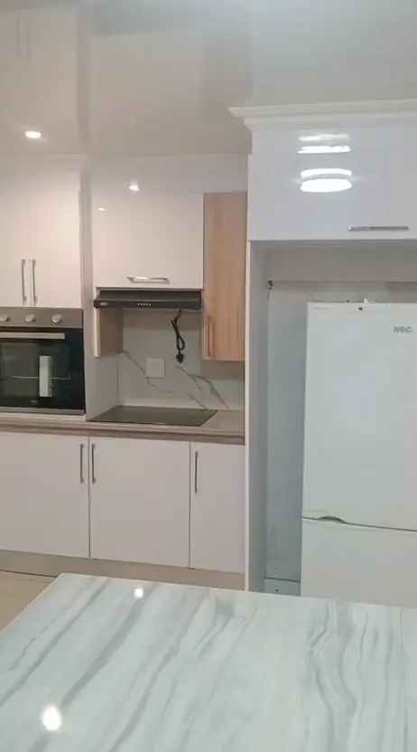 Still from a walk-through video of the white gloss kitchen with marble-effect island